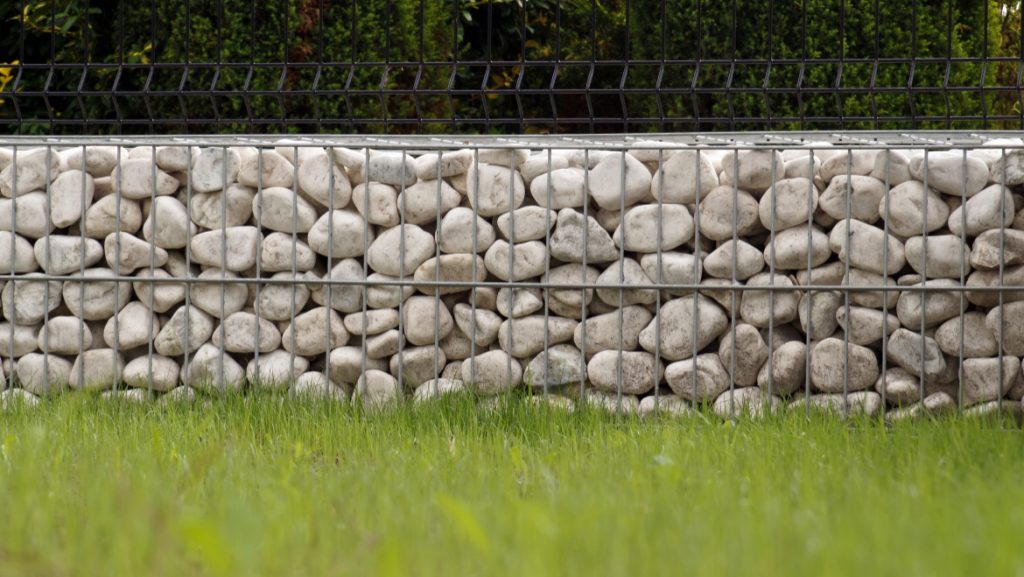 Impressive way of fencing the garden, metal baskets filled with white pebbles.